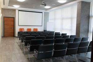 einen Konferenzraum mit Stühlen und einer Leinwand in der Unterkunft Taurus City Hotel in Lwiw