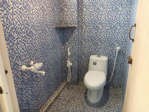 a bathroom with a toilet and blue tiled walls at Serene Deluxe Row Villa in Karumattampatti
