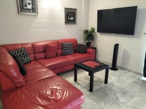 ロス・クリスティアーノスにあるDinastia Apartmentのリビングルーム(赤いソファ、薄型テレビ付)