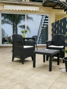 um pátio com 3 cadeiras, uma mesa e uma mesa em Terrazze sul golfo apartments em Castellammare del Golfo