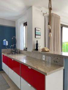 a kitchen with a counter with red and white cabinets at O Paraíso que você merece in Praia do Forte