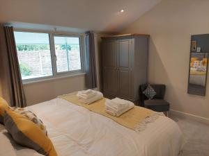 a bedroom with a large bed with two towels on it at Hazel in Bovey Tracey