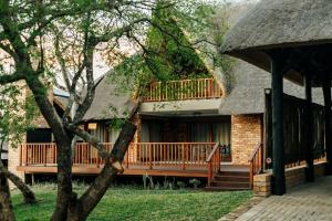 una casa con techo de paja y terraza en Kruger Park Lodge Unit 531 - PMP, en Hazyview