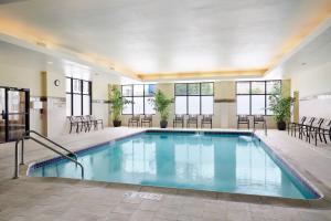 a pool in a hotel room with chairs and tables at Courtyard Milwaukee Downtown in Milwaukee