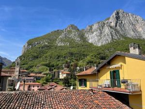 a yellow building with a mountain in the background at La casa del lago di lecco in Lecco