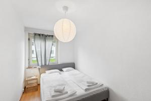 een witte slaapkamer met een bed en een kroonluchter bij Zurich Urban Charm: Your comfy stay close to the City in Zürich