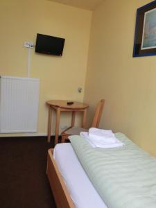 a room with a bed and a table and a television at Hotel Am Kleinbahnhof in Emden