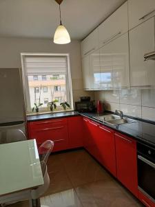 una cocina con armarios rojos y una ventana en Apartament u Oli i Laury, en Cracovia