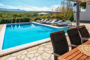 a swimming pool with chairs and a table at Peaceful Dream in Ercegovci