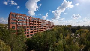 a tall brick building in the middle of trees at LUX Апартаменты SMART #7 in Pavlodar