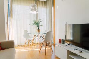 uma sala de estar com uma mesa com cadeiras e uma televisão em Oporto Yellow Apartments em Porto