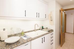 een witte badkamer met een wastafel en een spiegel bij Beach Paradise Flat in Denia Centre w/ Large Pool in Denia