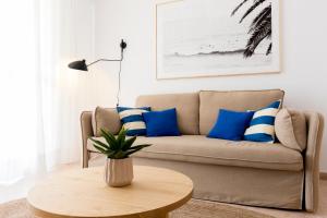 a living room with a couch with blue and white pillows at Beach Paradise Flat in Denia Centre w/ Large Pool in Denia