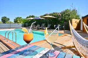 dos copas de bebidas en una mesa junto a una piscina en Gîte le Mizériat - Appartement avec piscine privée, en Saint-Didier-sur-Chalaronne