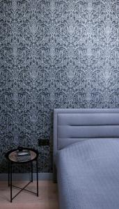 a bedroom with a bed and a table and wallpaper at The SiXth in Tukums