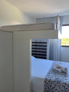 a bedroom with a white bed with a bunk bed at O Paraíso que você merece in Praia do Forte