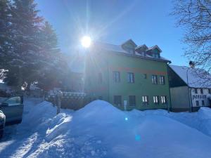 a building with the sun shining on top of snow at Chata Mamutka-New in Loučná pod Klínovcem