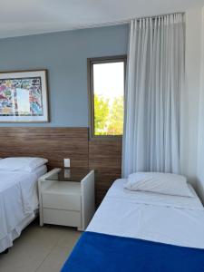 a bedroom with two beds and a window at O Paraíso que você merece in Praia do Forte