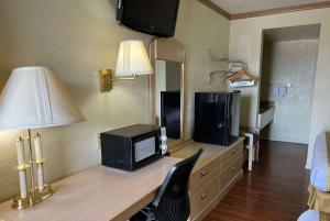 a room with a desk with a television and a lamp at Travelodge by Wyndham Holbrook in Holbrook