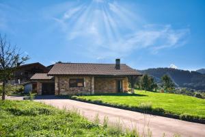 une maison en pierre sur une colline herbeuse avec un chemin dans l'établissement Basque Haven by Fidalsa, à Zeanuri