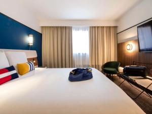 a hotel room with a large bed with a bag on it at Mercure Caen Centre Port De Plaisance in Caen