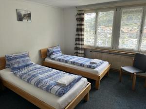 a room with two beds and a chair and windows at HOTEL CHRISTINA in Wilderswil