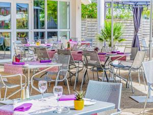 a group of tables and chairs with purple napkins at Mercure Tours Nord in Tours