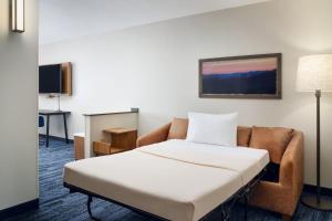 a hotel room with a bed and a couch at Fairfield Inn & Suites Auburn Opelika in Opelika
