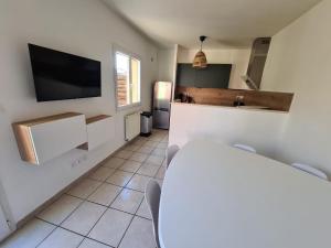 a living room with a television and a kitchen at Casa Papidou, Charmante Maison au calme in Jonage