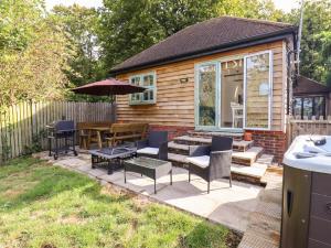 a patio with a table and chairs and an umbrella at Dreamwood Lodge in Keston