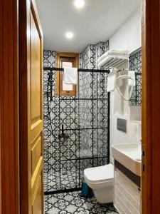 baño con aseo y azulejos blancos y negros en DIMORA HOTEL, en Estambul