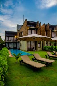 a building with a pool and some chairs and an umbrella at Inidi Leisure Luxury Villas in Wadduwa
