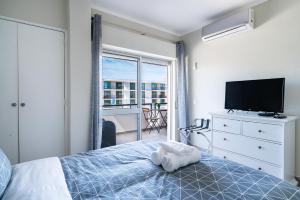 Un dormitorio con una cama y un televisor y un balcón. en Beachfront apartment in Armação, en Armação de Pêra