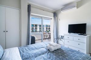 a bedroom with a bed and a television and a balcony at Beachfront apartment in Armação in Armação de Pêra