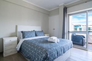 a bedroom with a bed and a large window at Beachfront apartment in Armação in Armação de Pêra