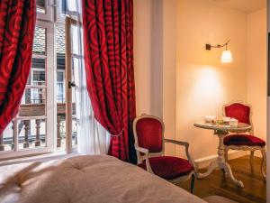 1 dormitorio con cama, mesa y ventana en Hotel Cour du Corbeau Strasbourg - MGallery en Estrasburgo