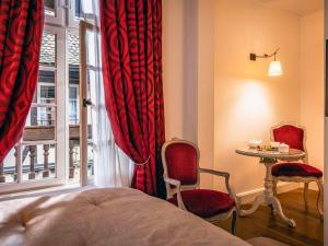 a bedroom with a bed and a table and a window at Hotel Cour du Corbeau Strasbourg - MGallery in Strasbourg