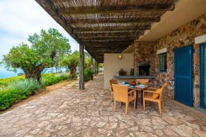 a patio with a table and chairs under a roof at Fattoria delle Ripalte in Capoliveri