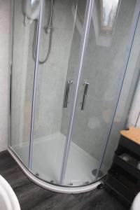 a shower with a glass door in a bathroom at The Hayloft, Marsden in Huddersfield