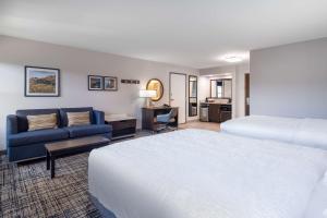 a hotel room with two beds and a blue couch at Hampton Inn & Suites Agoura Hills in Agoura Hills