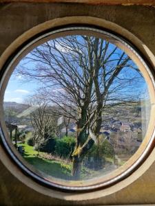 a round window with a view of a tree at The Hayloft, Marsden in Huddersfield
