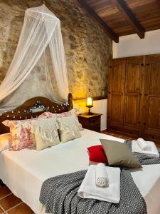 una camera da letto con un grande letto con lenzuola e cuscini bianchi di El latido del Tiétar a Lanzahita