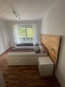 a bedroom with a bed with a wooden headboard and a window at FEWO CELINE in Wasserhofen