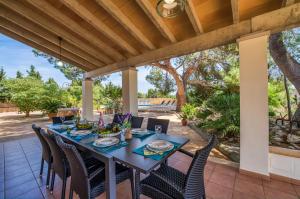 a dining table on a patio with chairs and a wooden ceiling at Ideal Property Mallorca - Can Ribas in Can Picafort