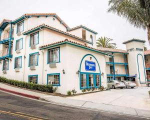 a large white building with blue trim on a street at Rodeway Inn San Clemente Beach in San Clemente