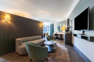 فندق راديسون بلو، غلاسكو في غلاسكو: غرفة في الفندق مع أريكة وكراسي وتلفزيون