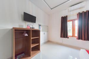 a living room with a tv and a book shelf at RedDoorz near Ciletuh Sukabumi in Cilowa