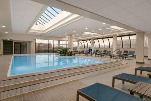 a pool in a building with tables and chairs at DoubleTree by Hilton Canton Downtown in Canton