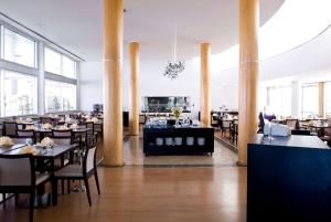 a restaurant with tables and chairs in a room with windows at TRYP by Wyndham Porto Expo Hotel in Leça da Palmeira