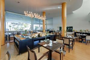 a restaurant with tables and chairs and a chandelier at TRYP by Wyndham Porto Expo Hotel in Leça da Palmeira